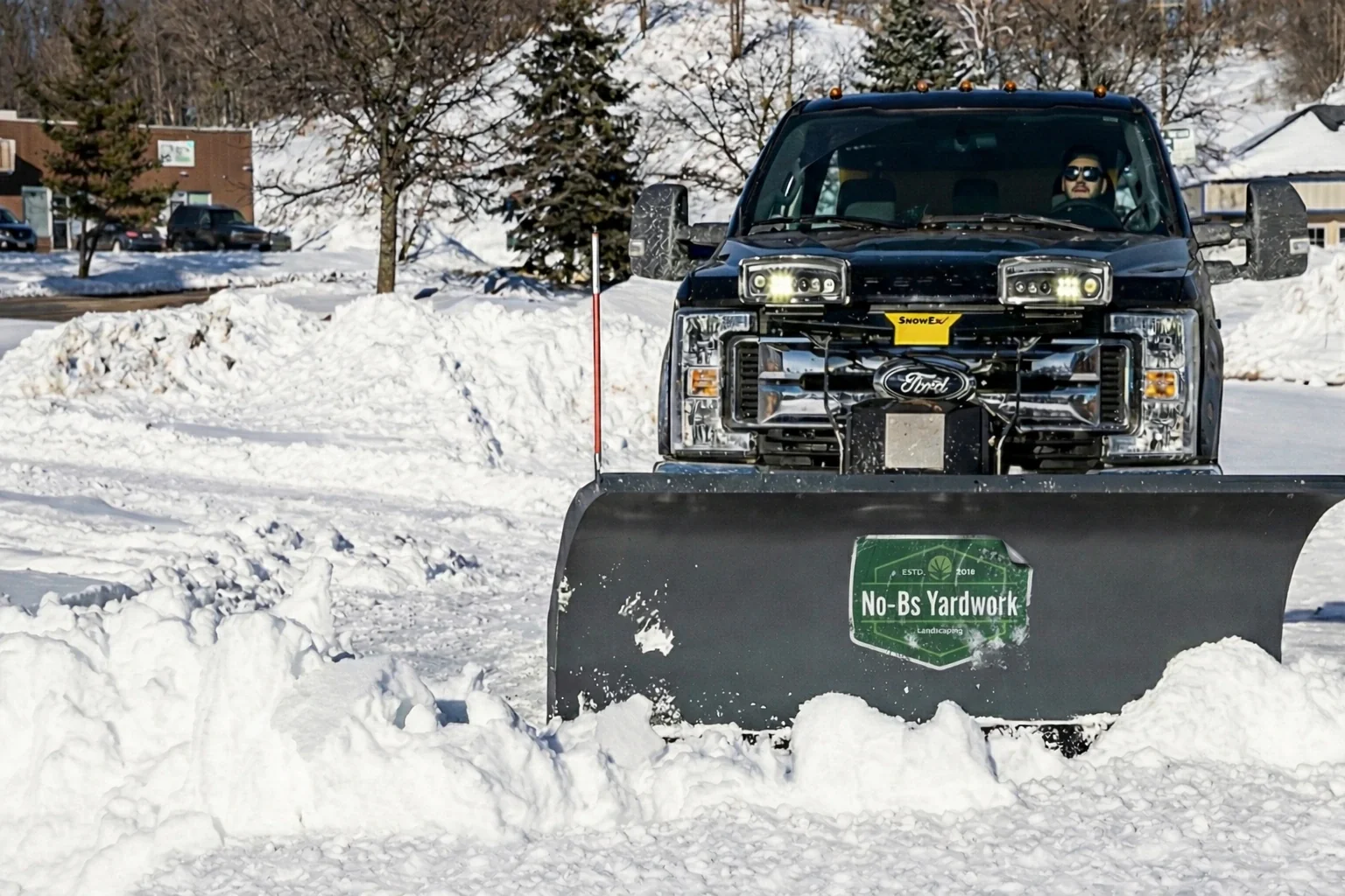 Snow plow truck clearing commercial parking lot in Winnipeg